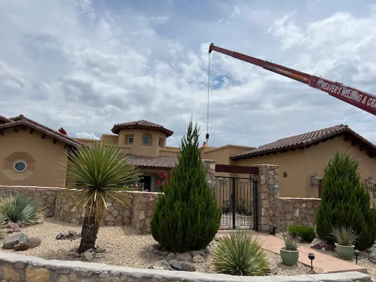 Crane operating over Spanish-style luxury home for HVAC install