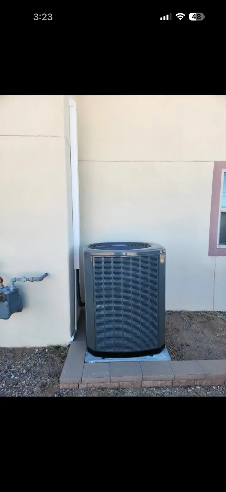Residential AC condenser by Las Cruces stucco home